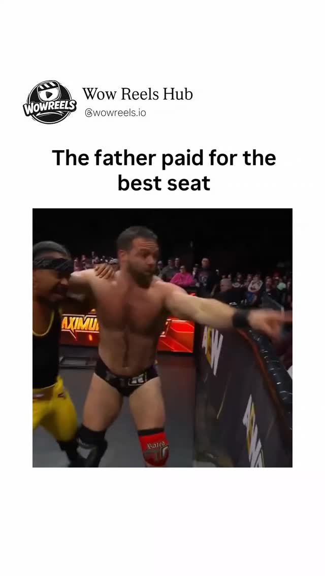 In a packed wrestling arena filled with cheering fans and bright red signage for "AEW CARNAGE," a muscular wrestler in a black tank top, yellow pants, and a bandana leans over the barrier toward a you