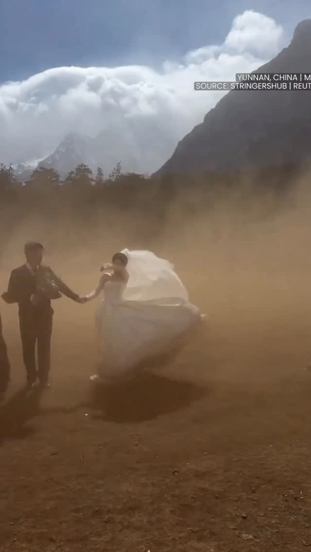 When I said sweep me off my feet this is NOT what I meant 😅 A couple in Yunnan was caught in sudden winds mid wedding photoshoot—but kept posing through the chaos… and somehow made it iconic. #China