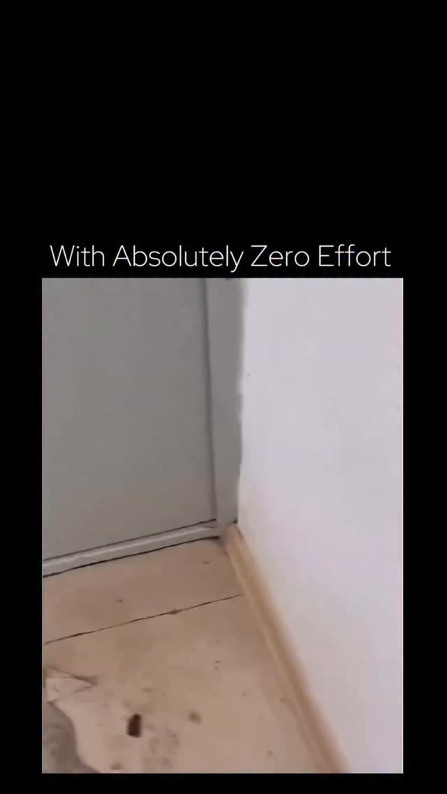 In this short video, titled with the caption "With Absolutely Zero Effort," the camera captures a first-person perspective of a person wearing black clogs and socks. Standing at a doorway that leads t